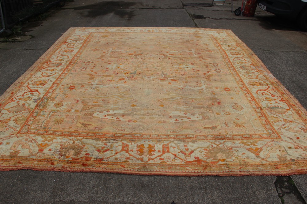 An oversized antique Turkish Oushak wool carpet featuring soft apricot, terracotta, and cream tones with traditional botanical borders and motifs. View IV