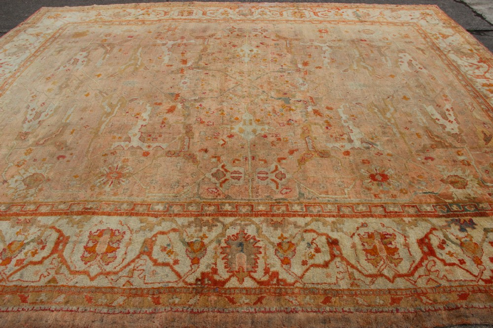 An oversized antique Turkish Oushak wool carpet featuring soft apricot, terracotta, and cream tones with traditional botanical borders and motifs. View VI