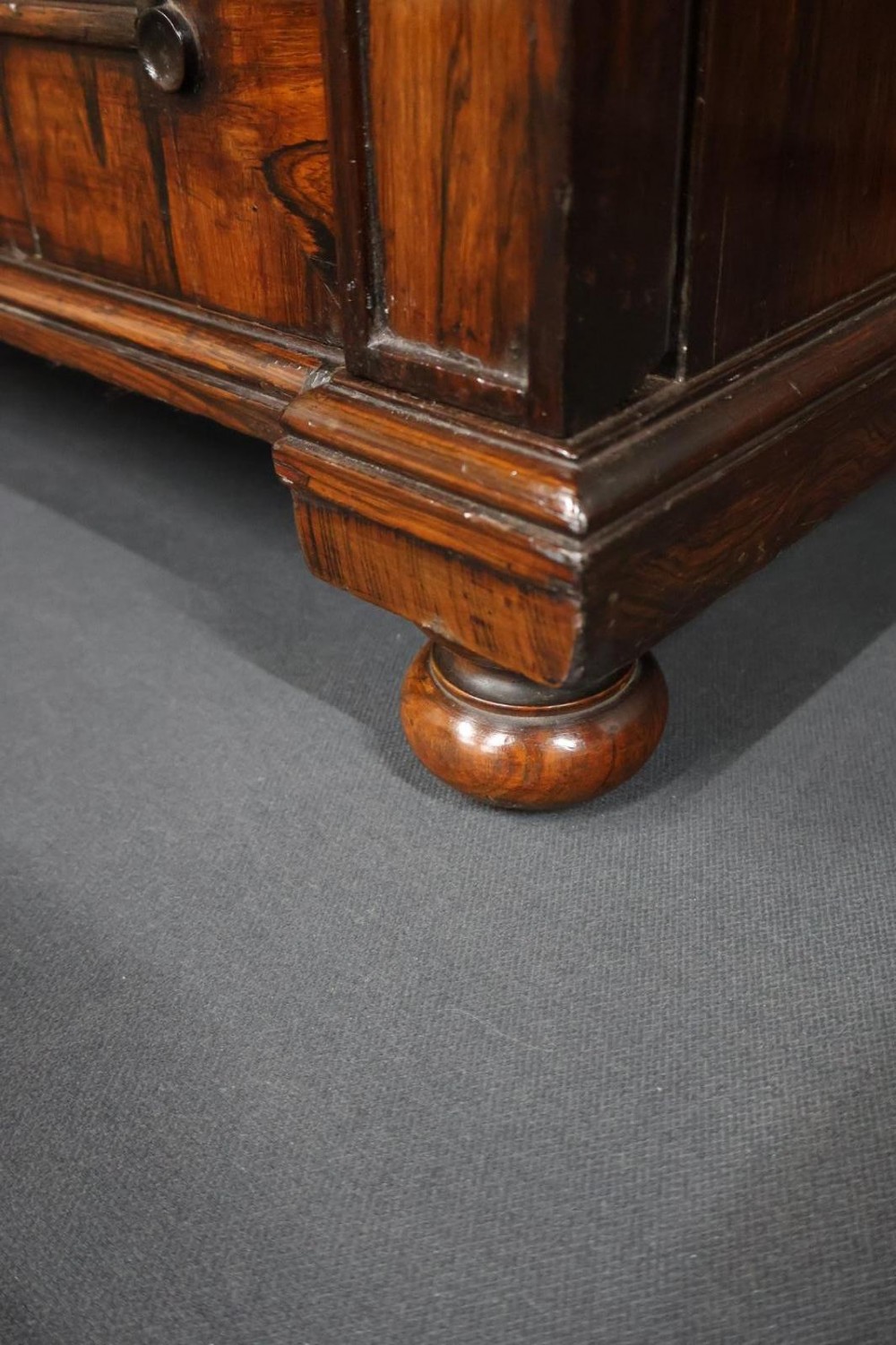 A Regency dark rosewood pier cabinet featuring a single glazed door revealing internal shelves, set on turned bun feet. View VII