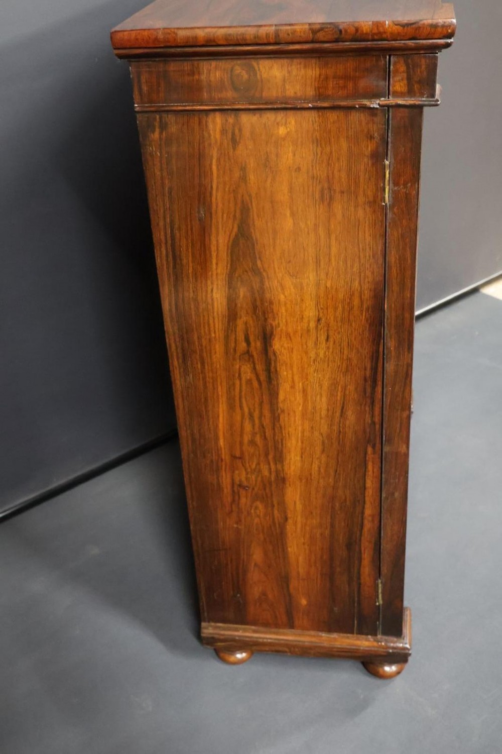 A Regency dark rosewood pier cabinet featuring a single glazed door revealing internal shelves, set on turned bun feet. View XI