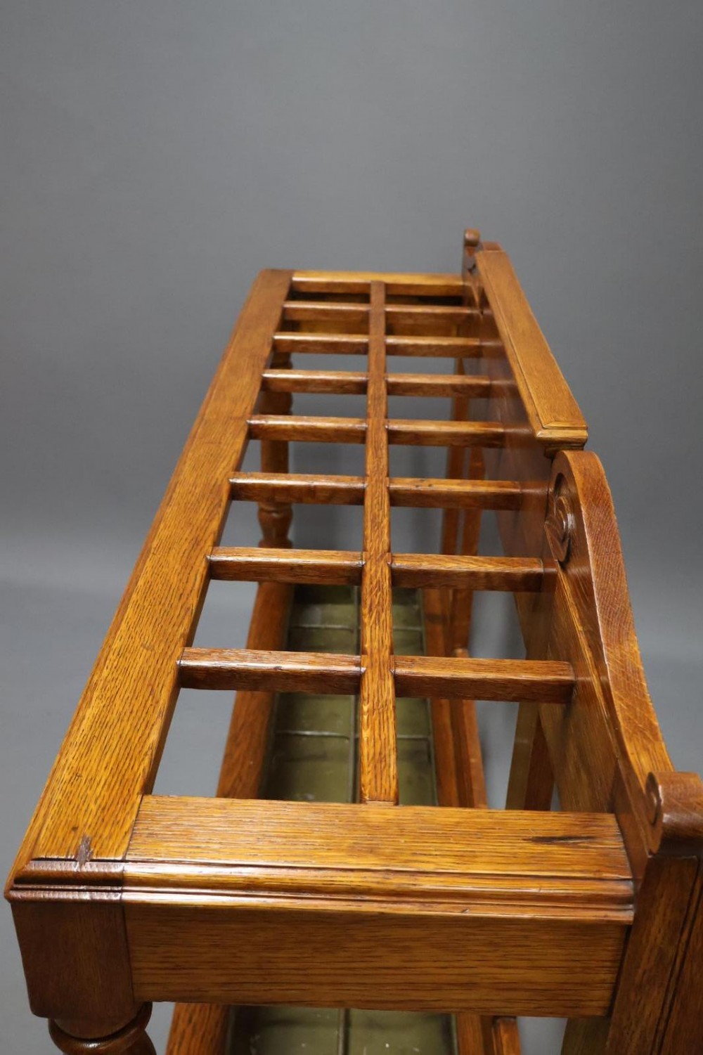 A large Victorian carved oak umbrella and stick stand featuring turned front supports, multiple upper divisions, and a metal drip tray at the base. View II