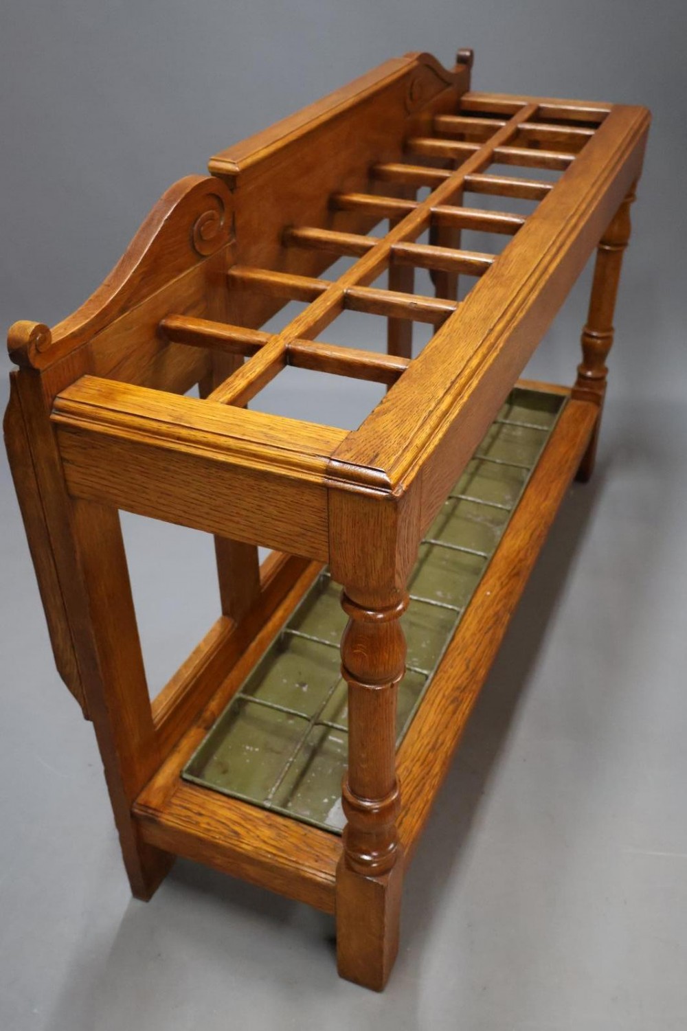 A large Victorian carved oak umbrella and stick stand featuring turned front supports, multiple upper divisions, and a metal drip tray at the base. View III