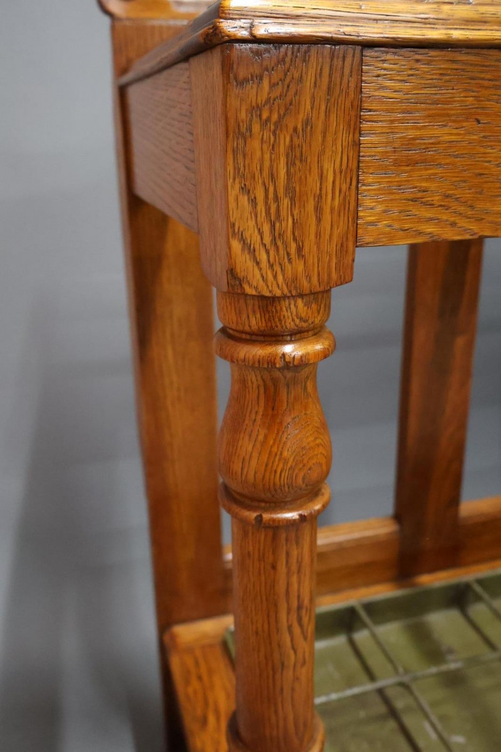 A large Victorian carved oak umbrella and stick stand featuring turned front supports, multiple upper divisions, and a metal drip tray at the base. View VII