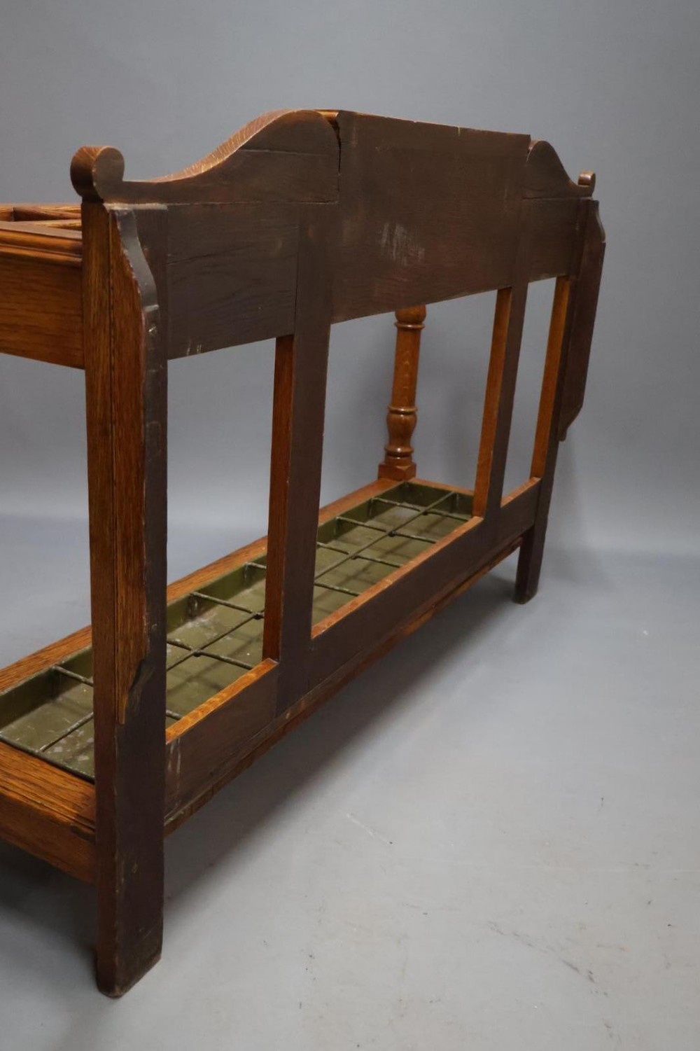 A large Victorian carved oak umbrella and stick stand featuring turned front supports, multiple upper divisions, and a metal drip tray at the base. View XI