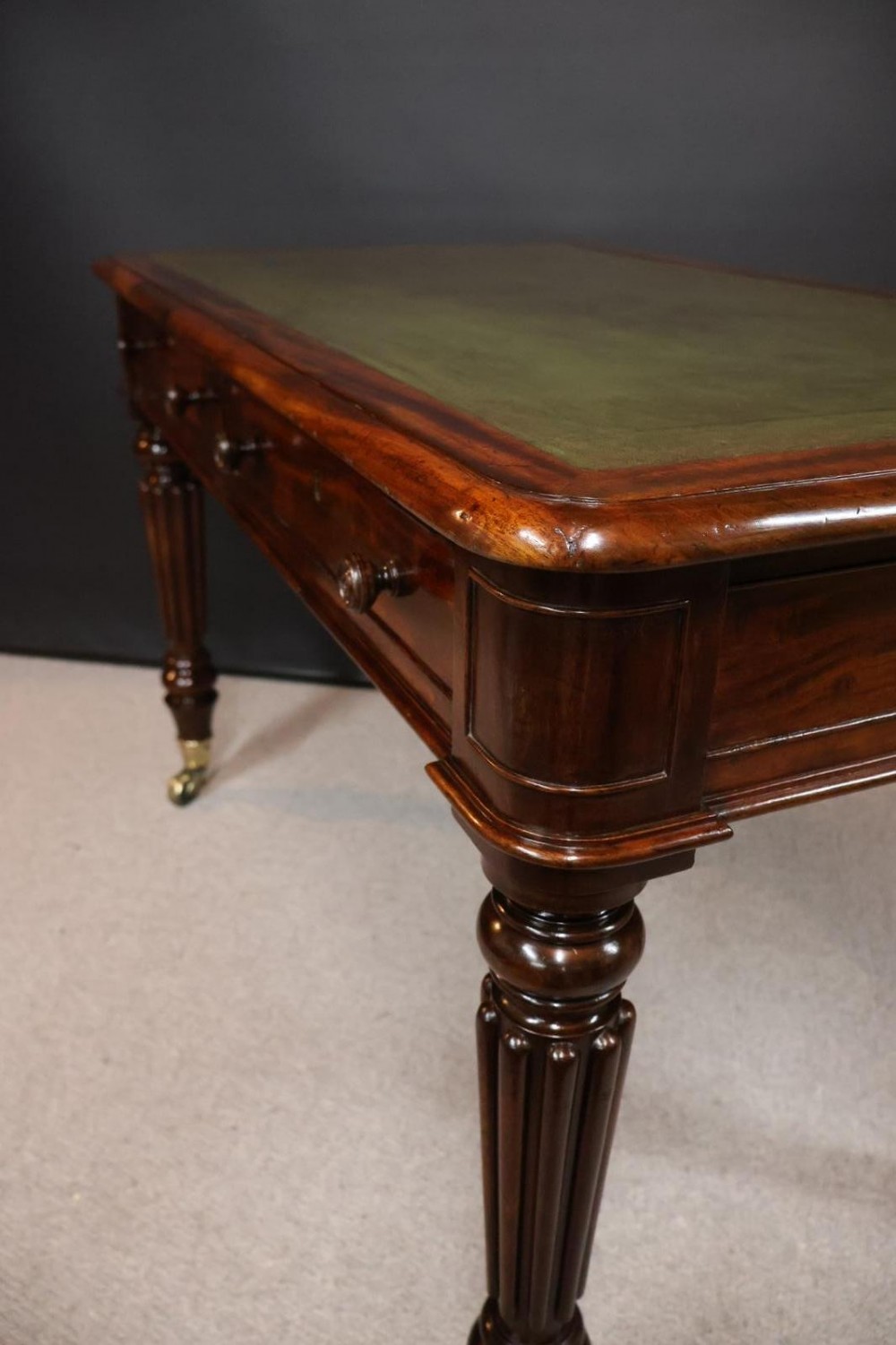An early nineteenth-century mahogany writing table featuring an inset green leather writing surface, two frieze drawers, and reeded turned legs on brass castors. View III