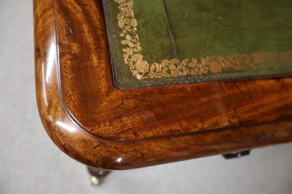 An early nineteenth-century mahogany writing table featuring an inset green leather writing surface, two frieze drawers, and reeded turned legs on brass castors. View V