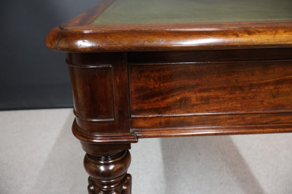 An early nineteenth-century mahogany writing table featuring an inset green leather writing surface, two frieze drawers, and reeded turned legs on brass castors. View VI