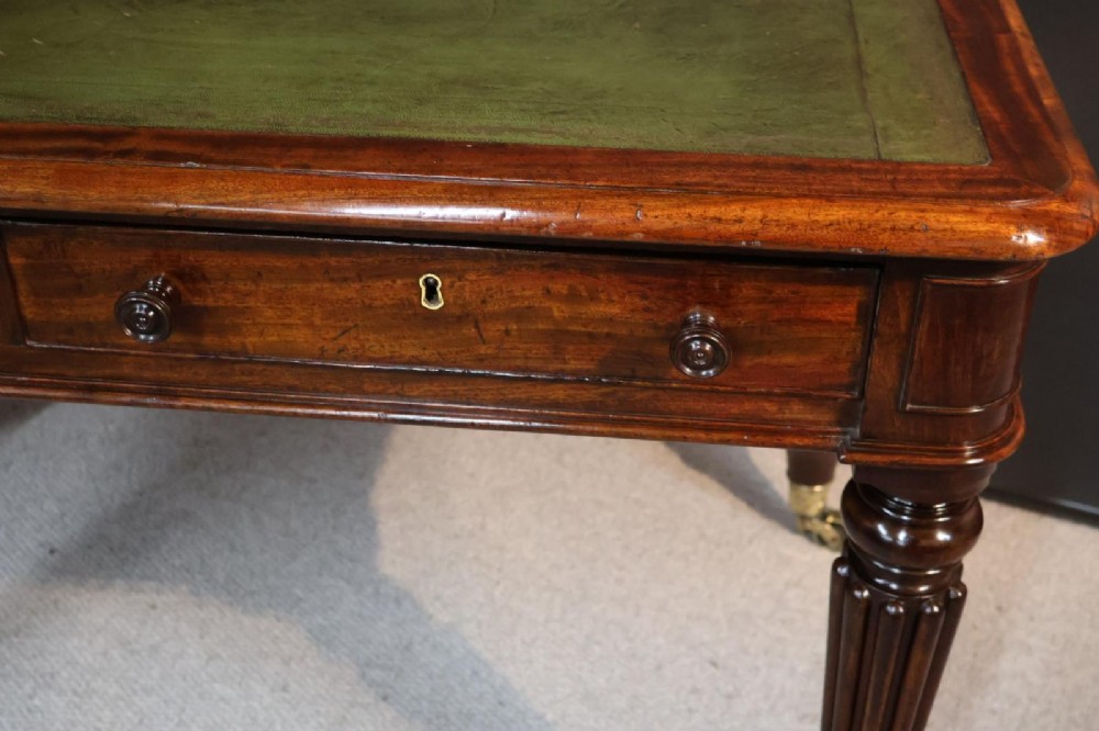 An early nineteenth-century mahogany writing table featuring an inset green leather writing surface, two frieze drawers, and reeded turned legs on brass castors. View IX