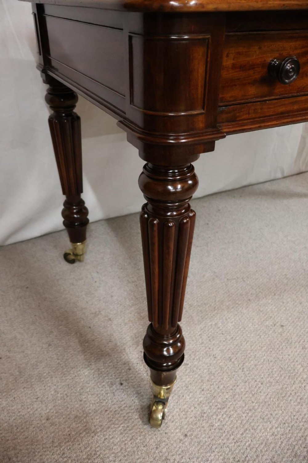 An early nineteenth-century mahogany writing table featuring an inset green leather writing surface, two frieze drawers, and reeded turned legs on brass castors. View XI