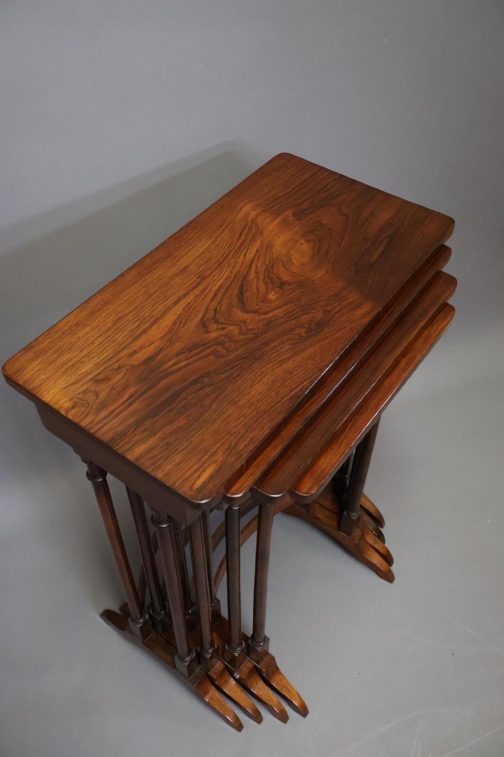 A set of four nested Regency rosewood tables featuring rectangular tops, slender turned spindle legs, and curved lower stretchers. View II