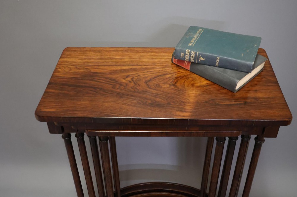 A set of four nested Regency rosewood tables featuring rectangular tops, slender turned spindle legs, and curved lower stretchers. View III