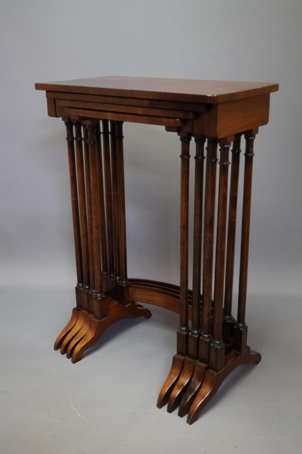 A set of four nested Regency rosewood tables featuring rectangular tops, slender turned spindle legs, and curved lower stretchers. View IV