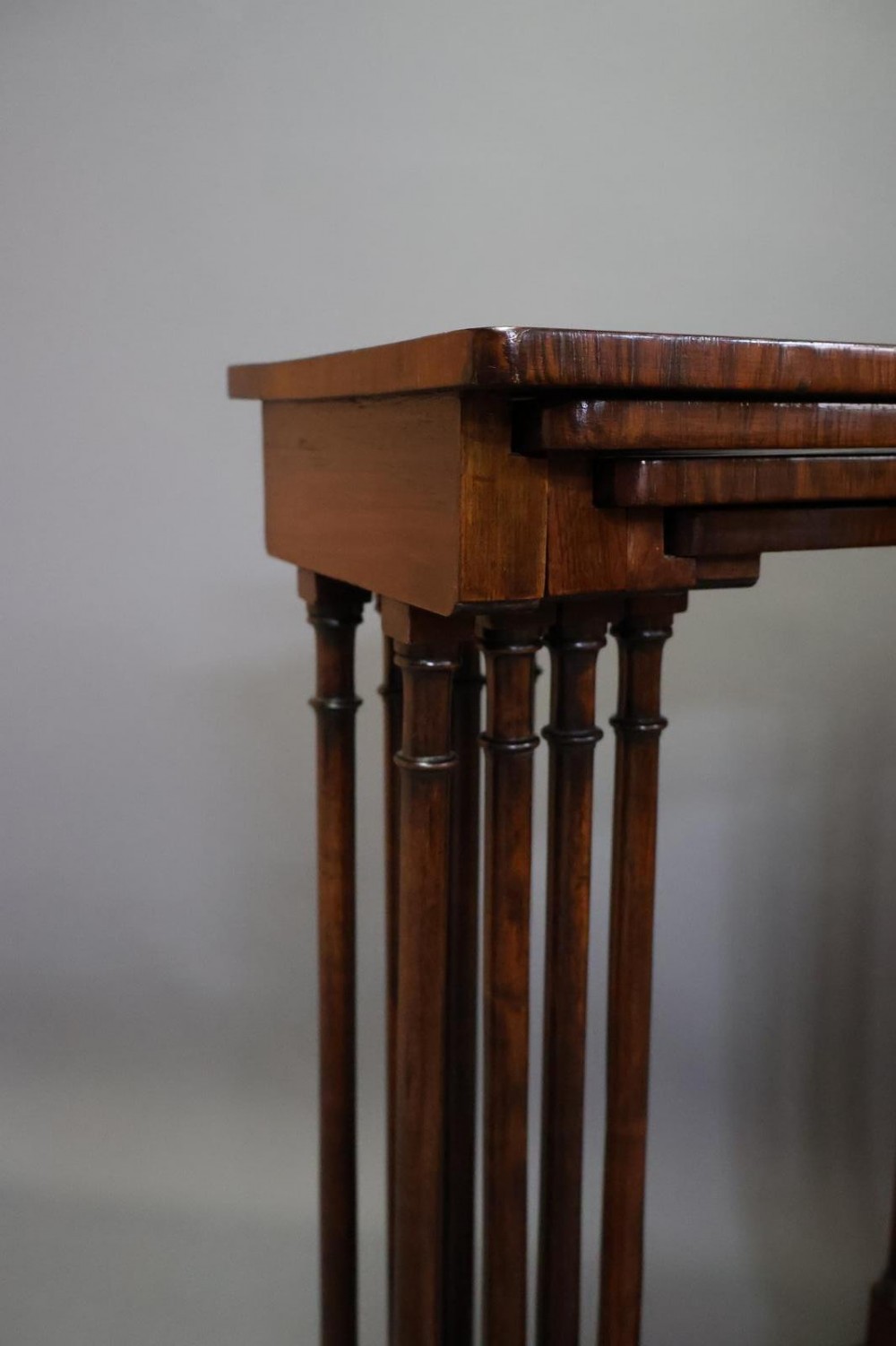 A set of four nested Regency rosewood tables featuring rectangular tops, slender turned spindle legs, and curved lower stretchers. View VII