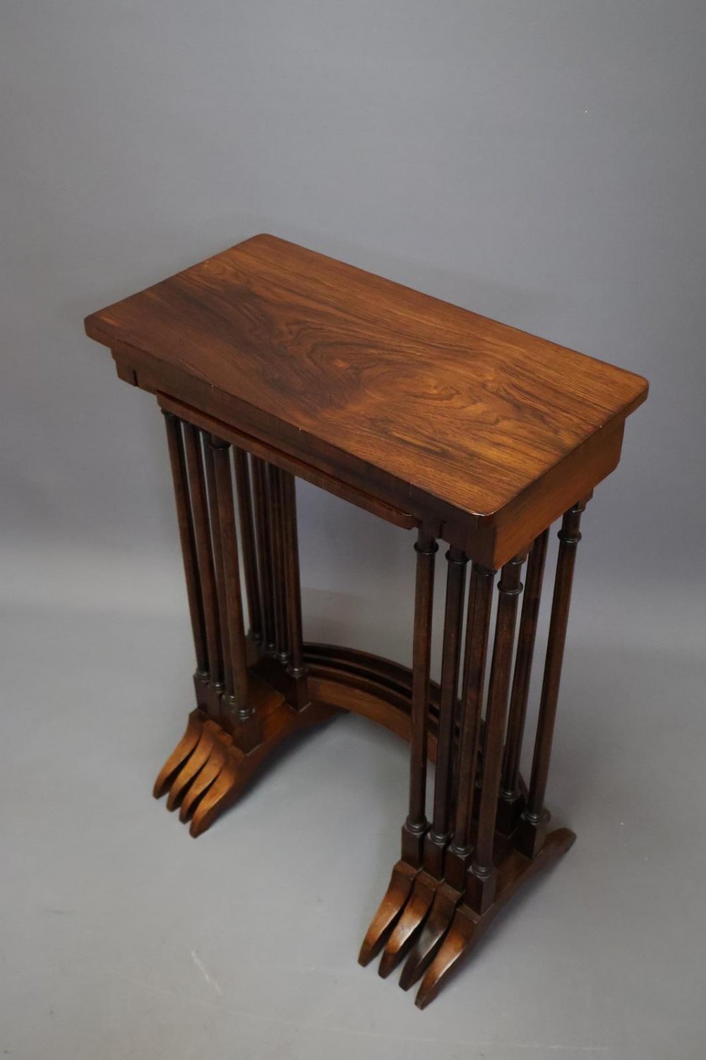 A set of four nested Regency rosewood tables featuring rectangular tops, slender turned spindle legs, and curved lower stretchers. View VIII