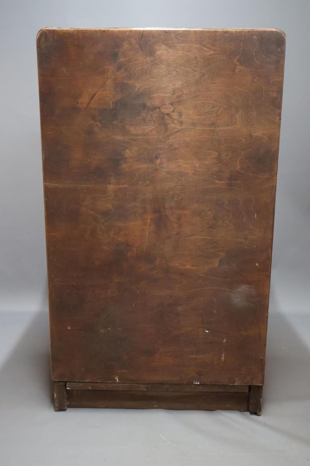An Art Deco walnut tallboy chest of drawers featuring eight vertically stacked drawers with figured wood grain, round black handles, and an ebonised base. View XI
