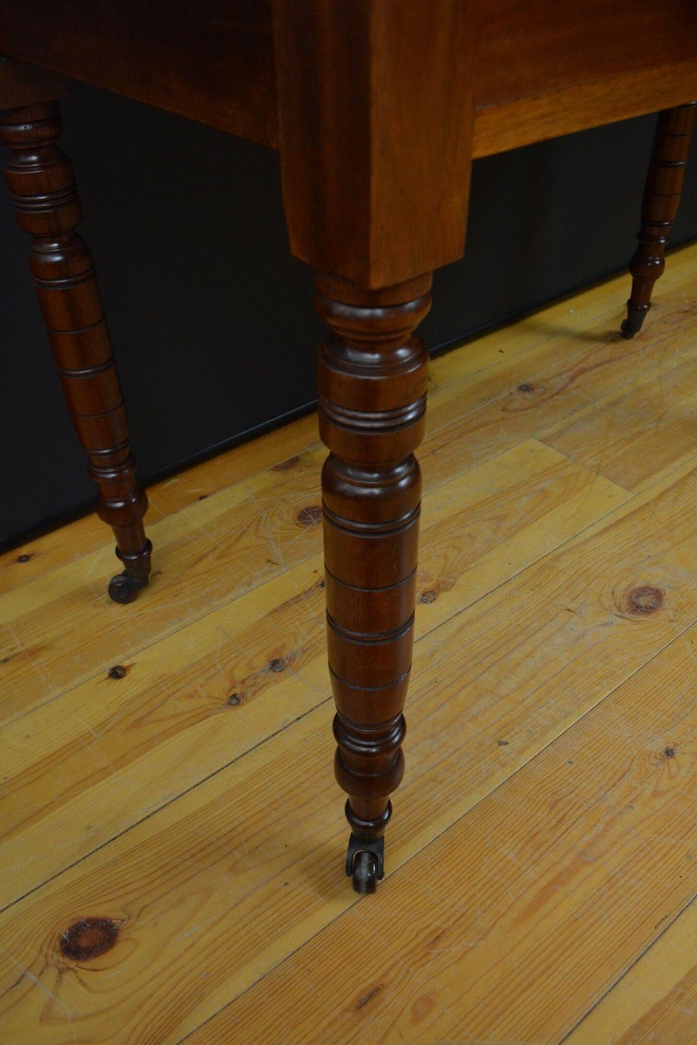 An Edwardian mahogany dressing table featuring a central rectangular mirror flanked by small jewellery drawers, resting on turned legs with brass casters. View III