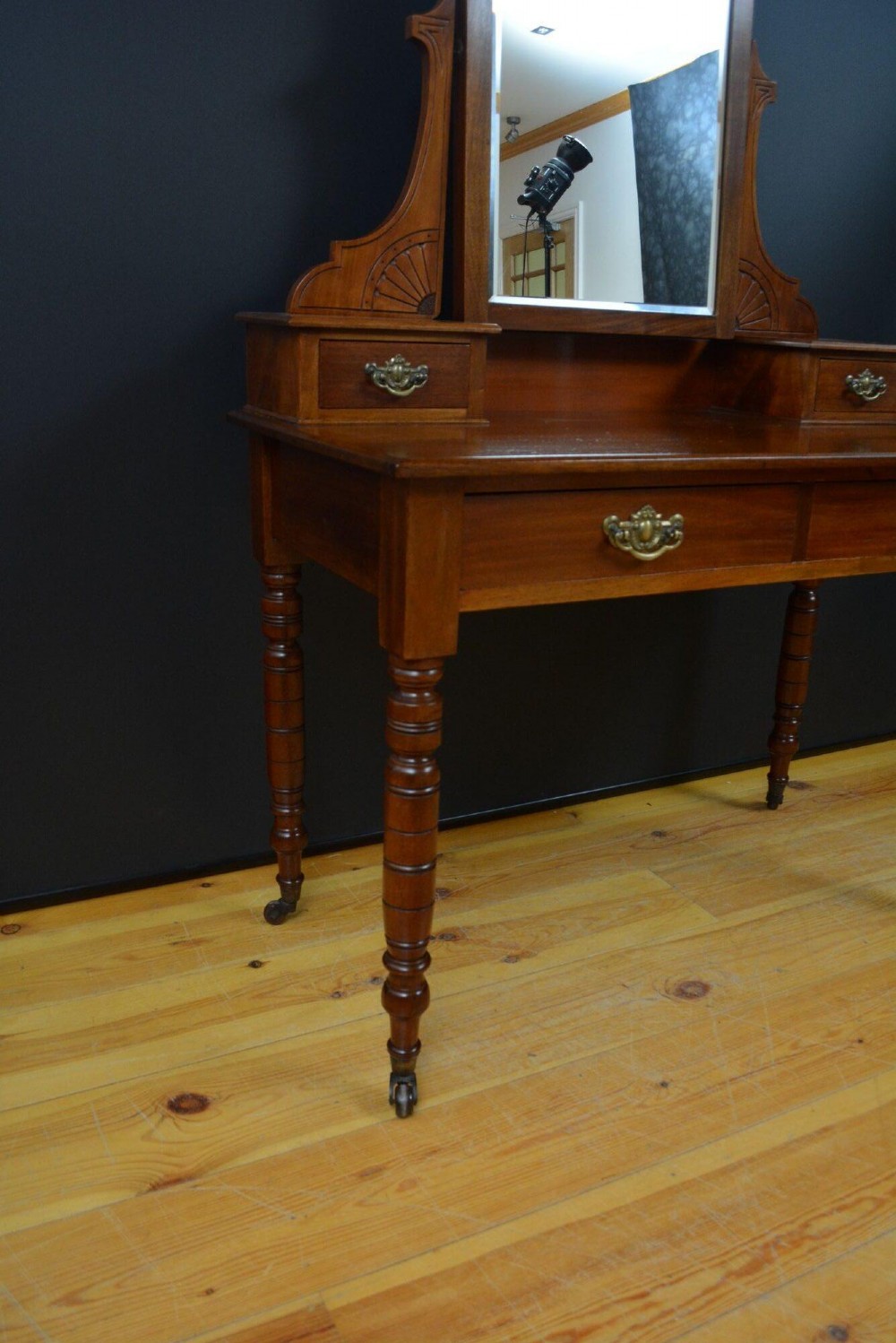 An Edwardian mahogany dressing table featuring a central rectangular mirror flanked by small jewellery drawers, resting on turned legs with brass casters. View IV