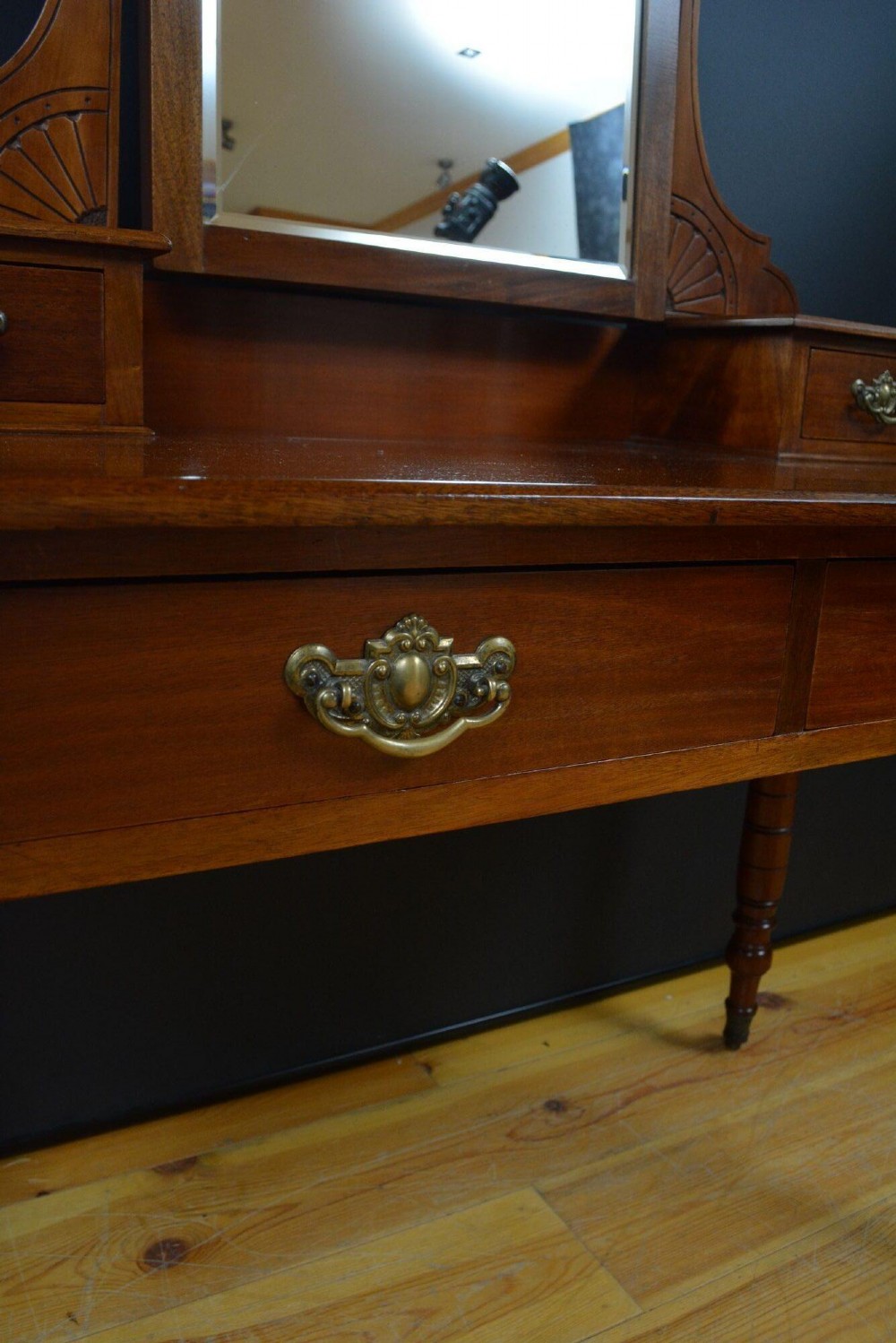An Edwardian mahogany dressing table featuring a central rectangular mirror flanked by small jewellery drawers, resting on turned legs with brass casters. View VI