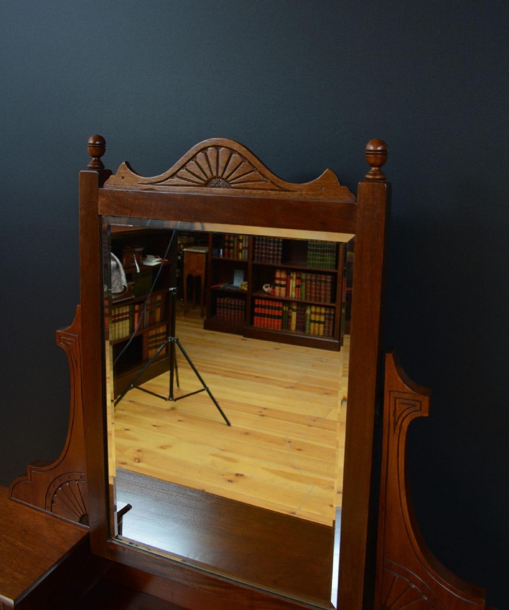 An Edwardian mahogany dressing table featuring a central rectangular mirror flanked by small jewellery drawers, resting on turned legs with brass casters. View X