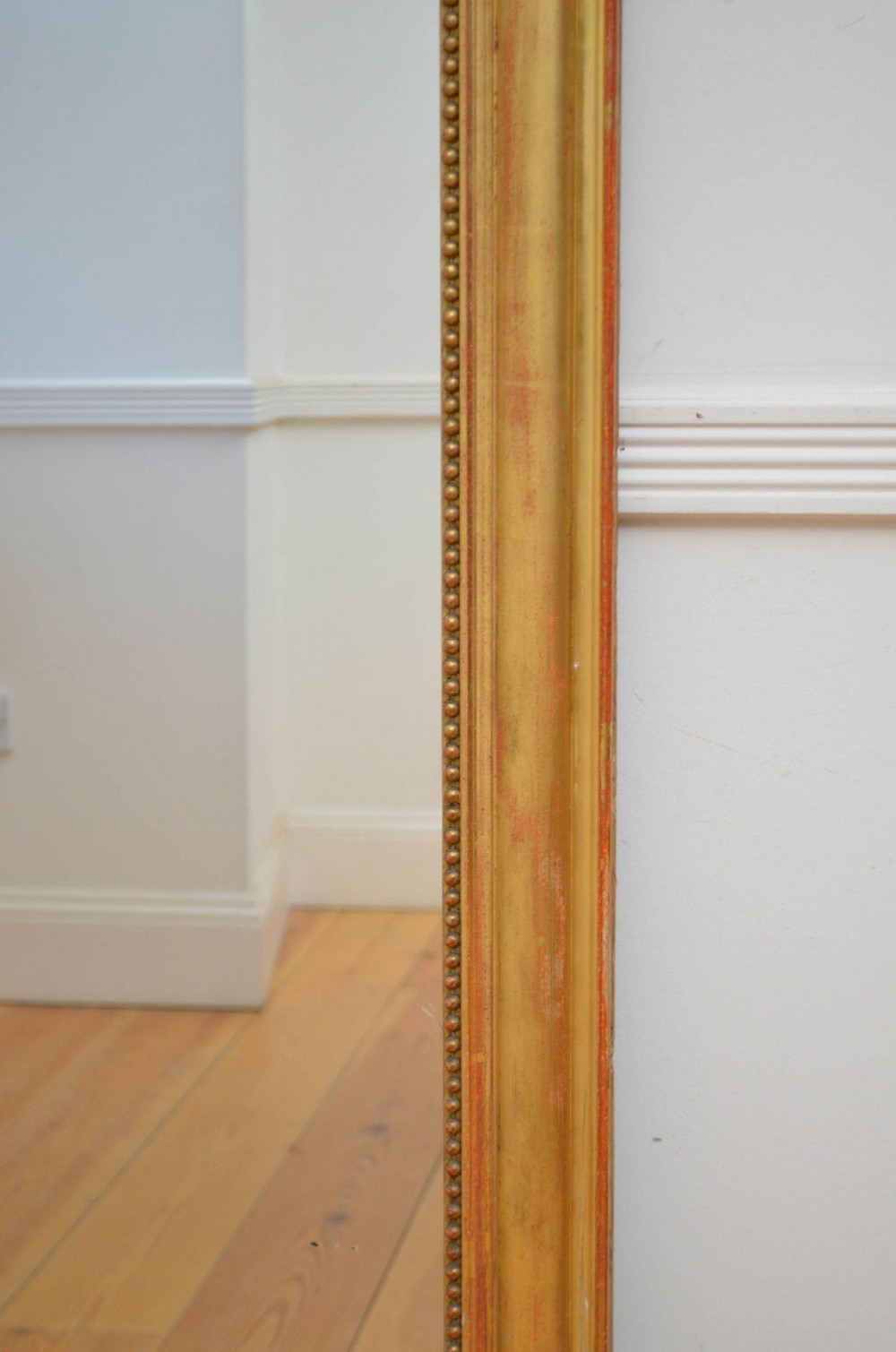 A large rectangular French antique wall mirror featuring a giltwood frame with fine bead moulding around the inner sight edge. View VII