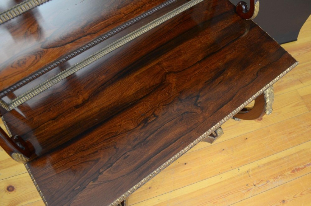 A Regency rosewood console table featuring an upper shelf tier, mirror-backed panels, and gilt carved scroll legs. View III