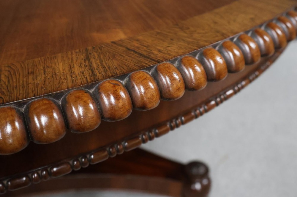A Regency circular flame mahogany centre table shown in a tilted position on a curved triform base. View VII