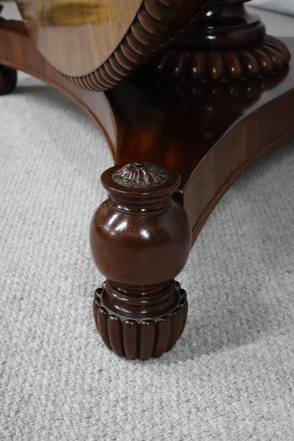 A Regency circular flame mahogany centre table shown in a tilted position on a curved triform base. View IX