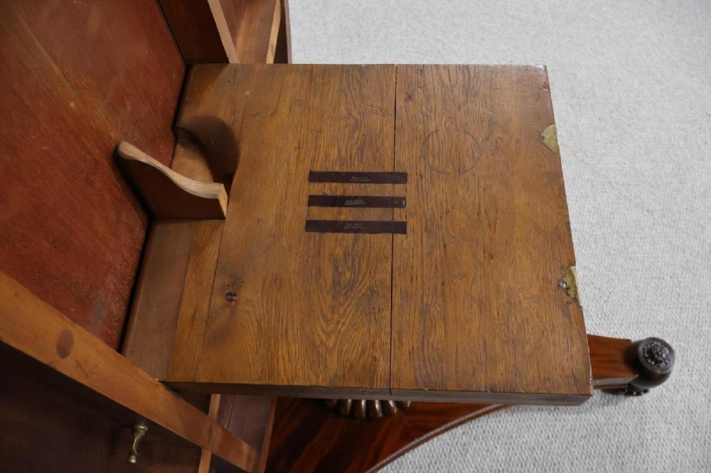 A Regency circular flame mahogany centre table shown in a tilted position on a curved triform base. View X