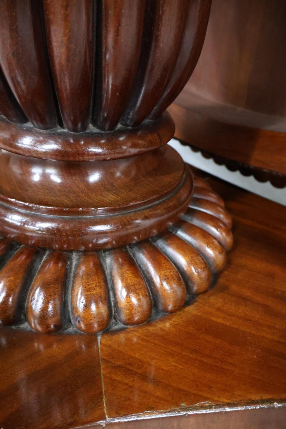 A Regency circular flame mahogany centre table shown in a tilted position on a curved triform base. View XII