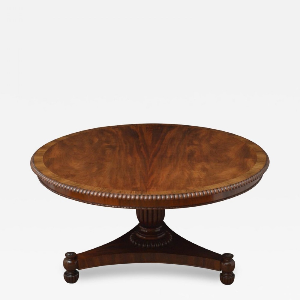 A Regency circular flame mahogany centre table shown in a tilted position on a curved triform base. View II