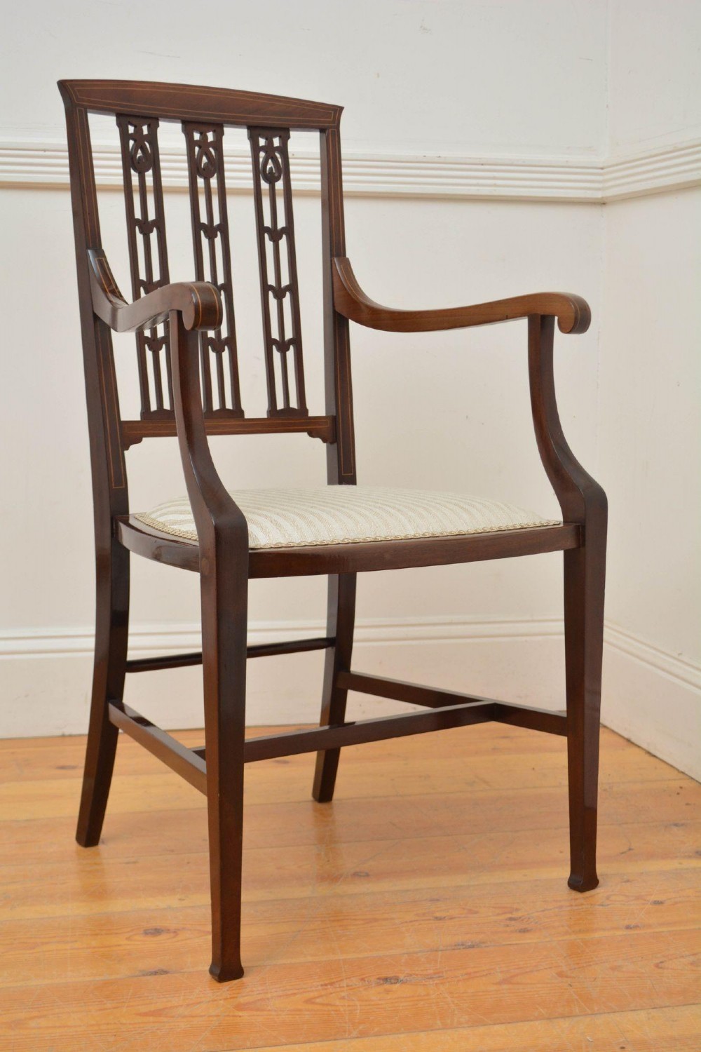 An Art Nouveau mahogany armchair featuring a pierced back splat with inlaid detailing, swept armrests, and a cream striped upholstered seat. View II