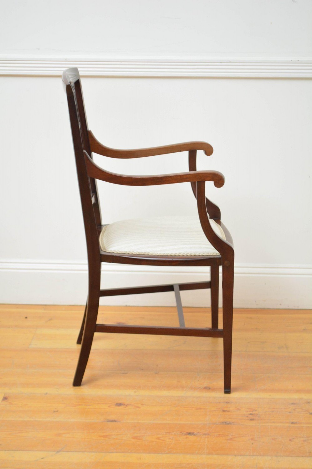 An Art Nouveau mahogany armchair featuring a pierced back splat with inlaid detailing, swept armrests, and a cream striped upholstered seat. View III