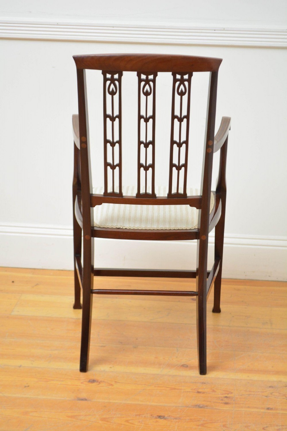 An Art Nouveau mahogany armchair featuring a pierced back splat with inlaid detailing, swept armrests, and a cream striped upholstered seat. View VII