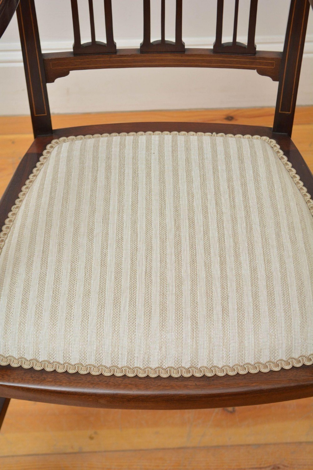 An Art Nouveau mahogany armchair featuring a pierced back splat with inlaid detailing, swept armrests, and a cream striped upholstered seat. View VIII