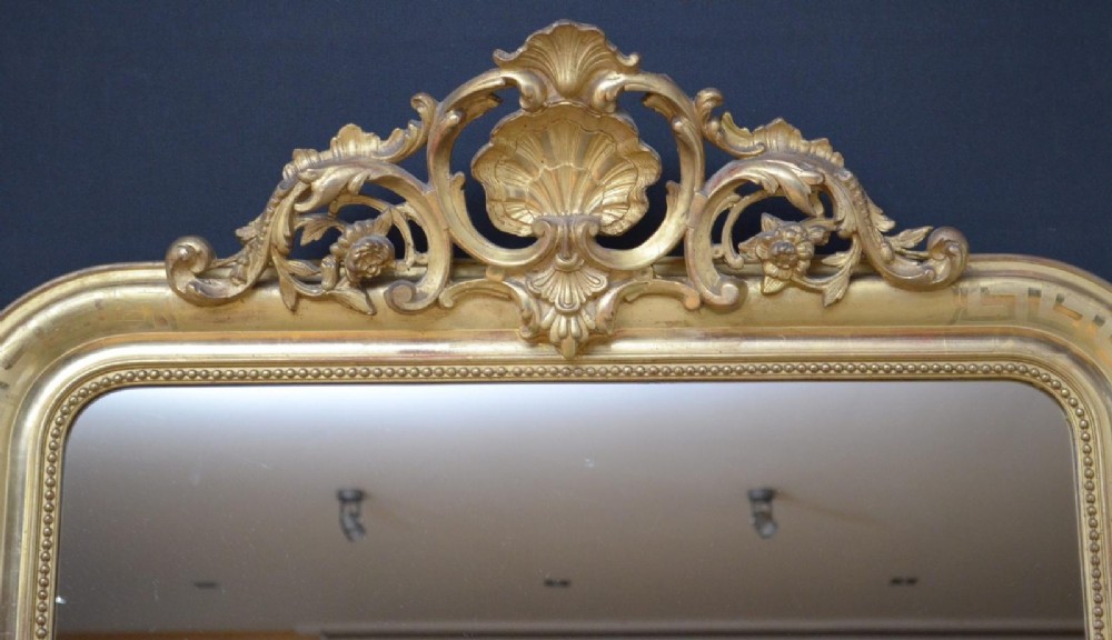 A 19th-century French wall mirror featuring a rectangular frame with rounded top corners, a gold leaf finish, and an ornate carved shell cresting. View III