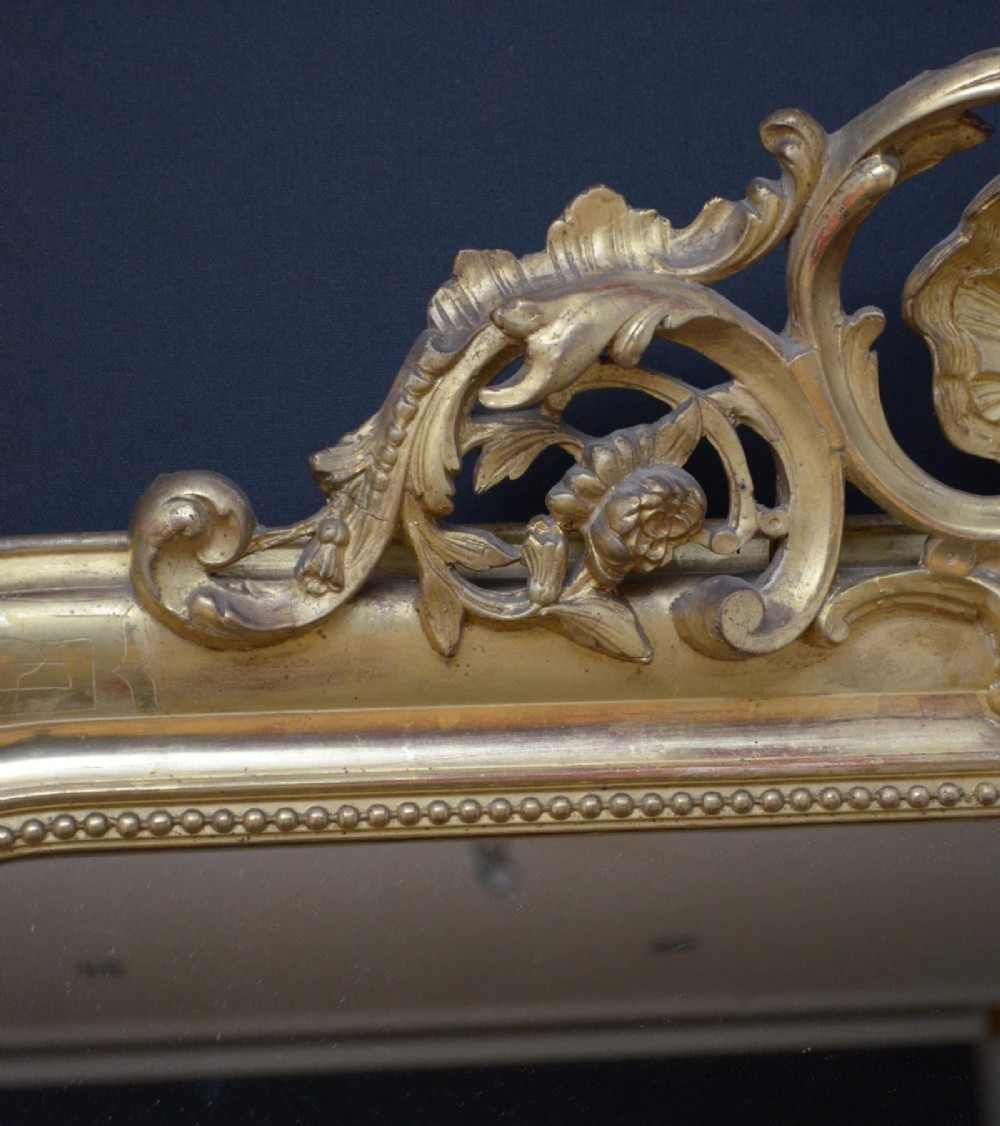 A 19th-century French wall mirror featuring a rectangular frame with rounded top corners, a gold leaf finish, and an ornate carved shell cresting. View IV