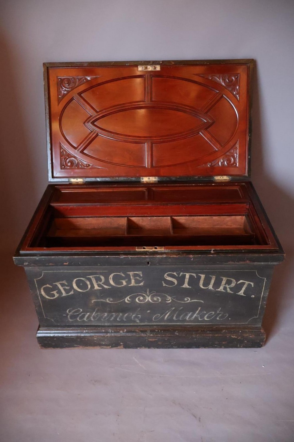 A Victorian painted wooden cabinet makers tool chest with hand-painted lettering on the front exterior and a mahogany fitted interior with geometric lid panelling.