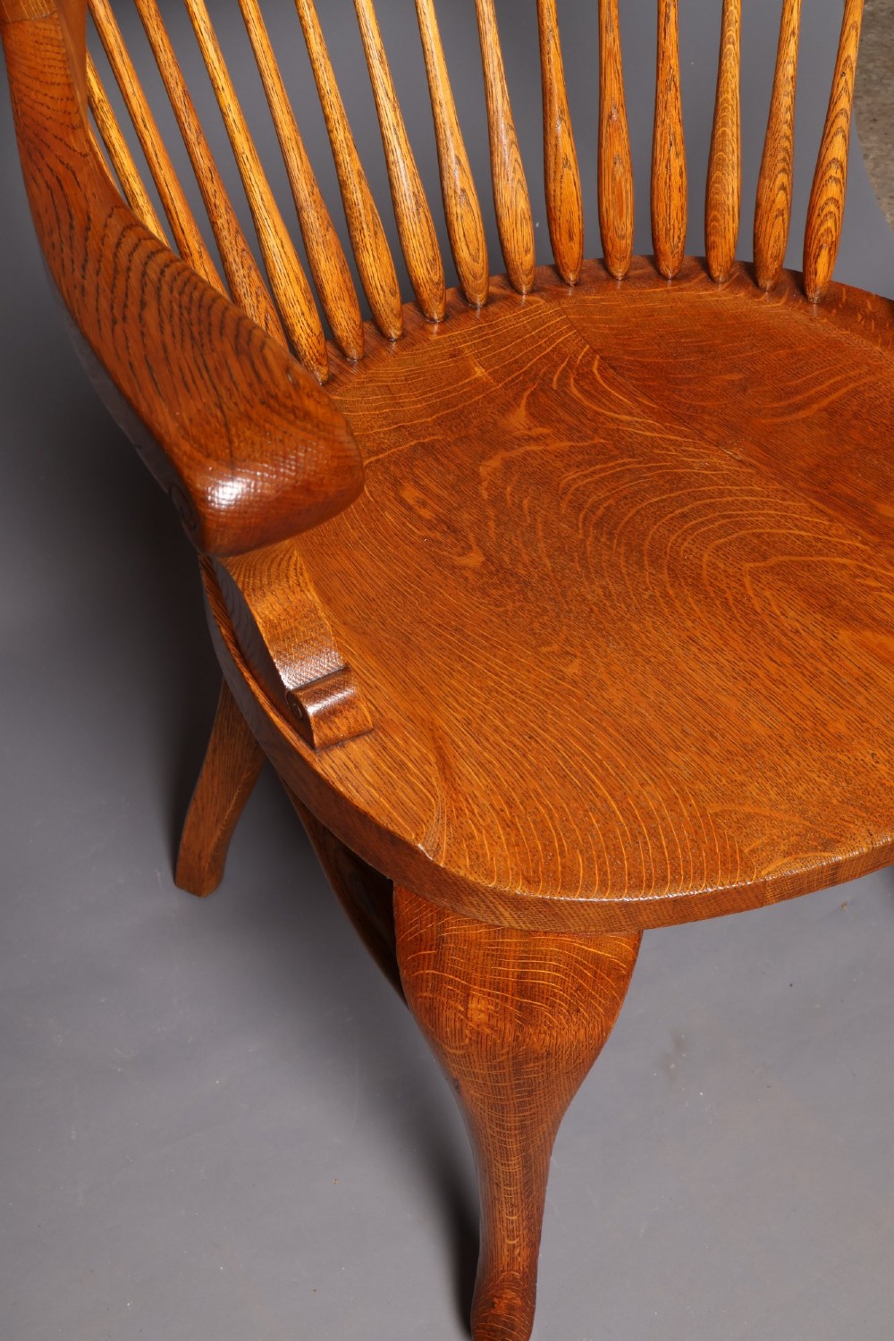 An antique Victorian golden oak desk chair featuring a curved spindle back, curved armrests, a contoured seat, and cabriole front legs. View VII