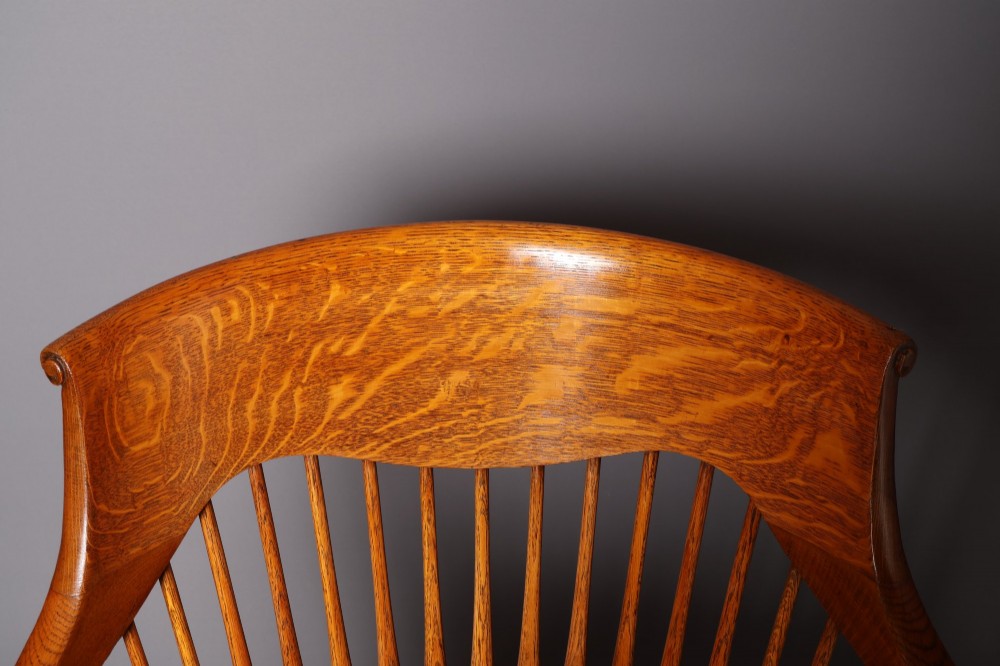 An antique Victorian golden oak desk chair featuring a curved spindle back, curved armrests, a contoured seat, and cabriole front legs. View VIII