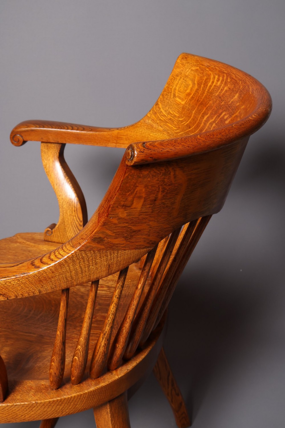 An antique Victorian golden oak desk chair featuring a curved spindle back, curved armrests, a contoured seat, and cabriole front legs. View IX