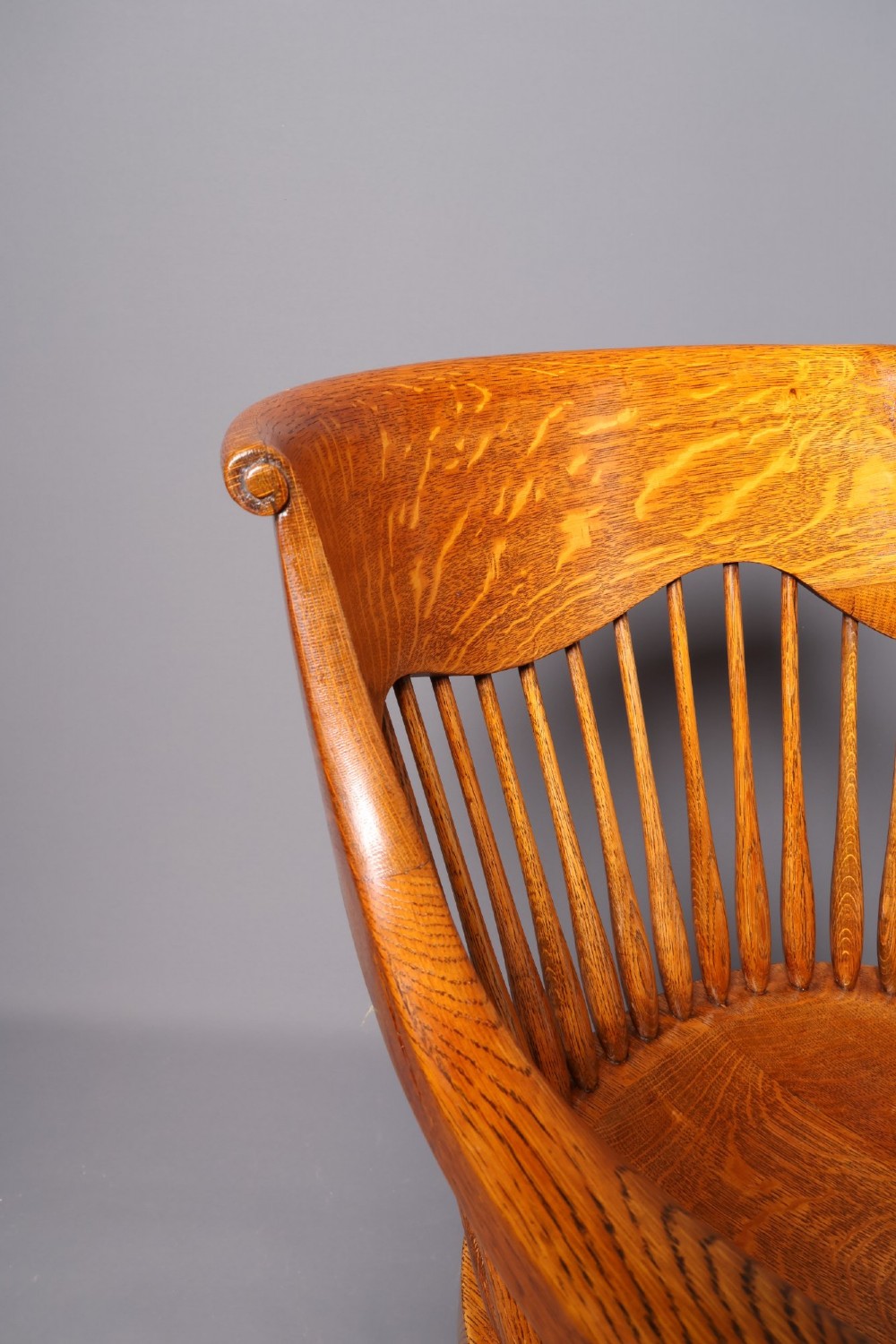 An antique Victorian golden oak desk chair featuring a curved spindle back, curved armrests, a contoured seat, and cabriole front legs. View XII