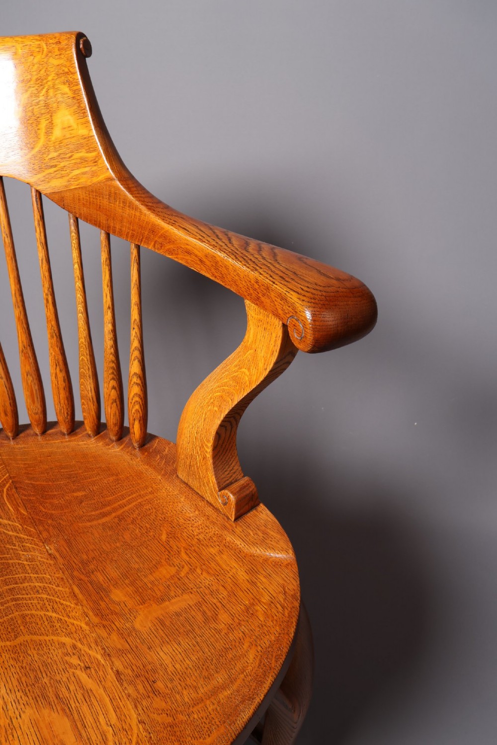 An antique Victorian golden oak desk chair featuring a curved spindle back, curved armrests, a contoured seat, and cabriole front legs. View XV