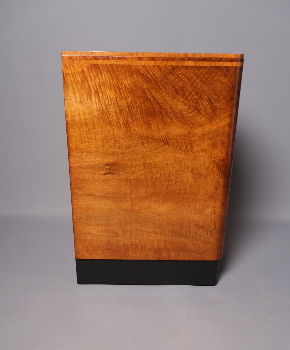 A matching pair of tall Art Deco burr walnut bedside cabinets with three drawers, dark curved handles, and ebonised plinth bases. View IX