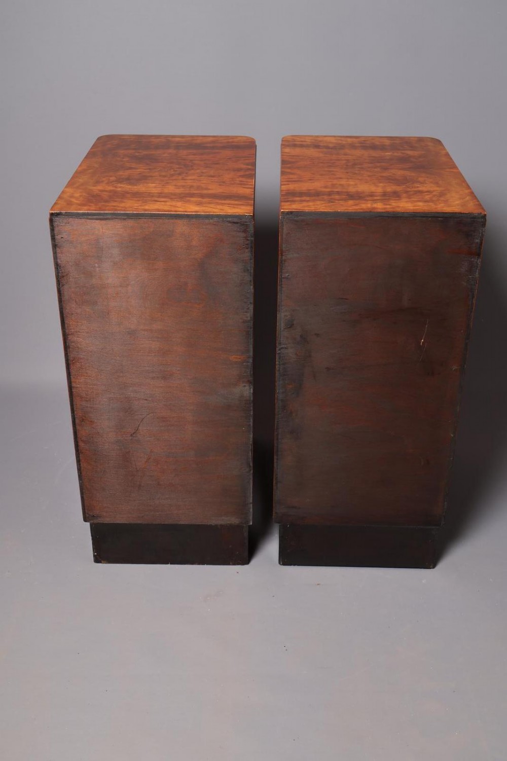 A matching pair of tall Art Deco burr walnut bedside cabinets with three drawers, dark curved handles, and ebonised plinth bases. View XII