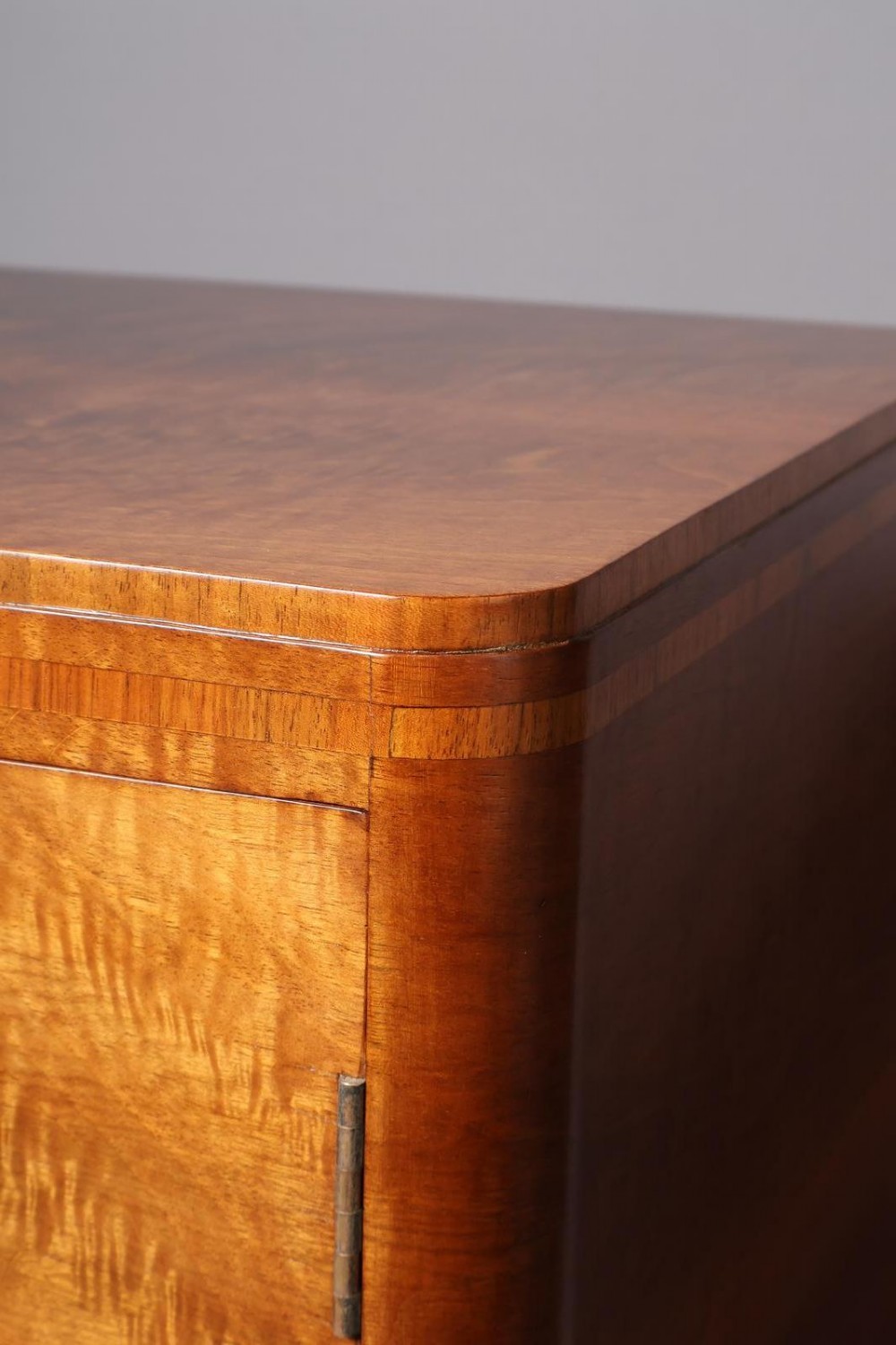 An Art Deco burr walnut compactum wardrobe featuring upper double doors, two long lower drawers, black curved handles, and an ebonised plinth. View VI