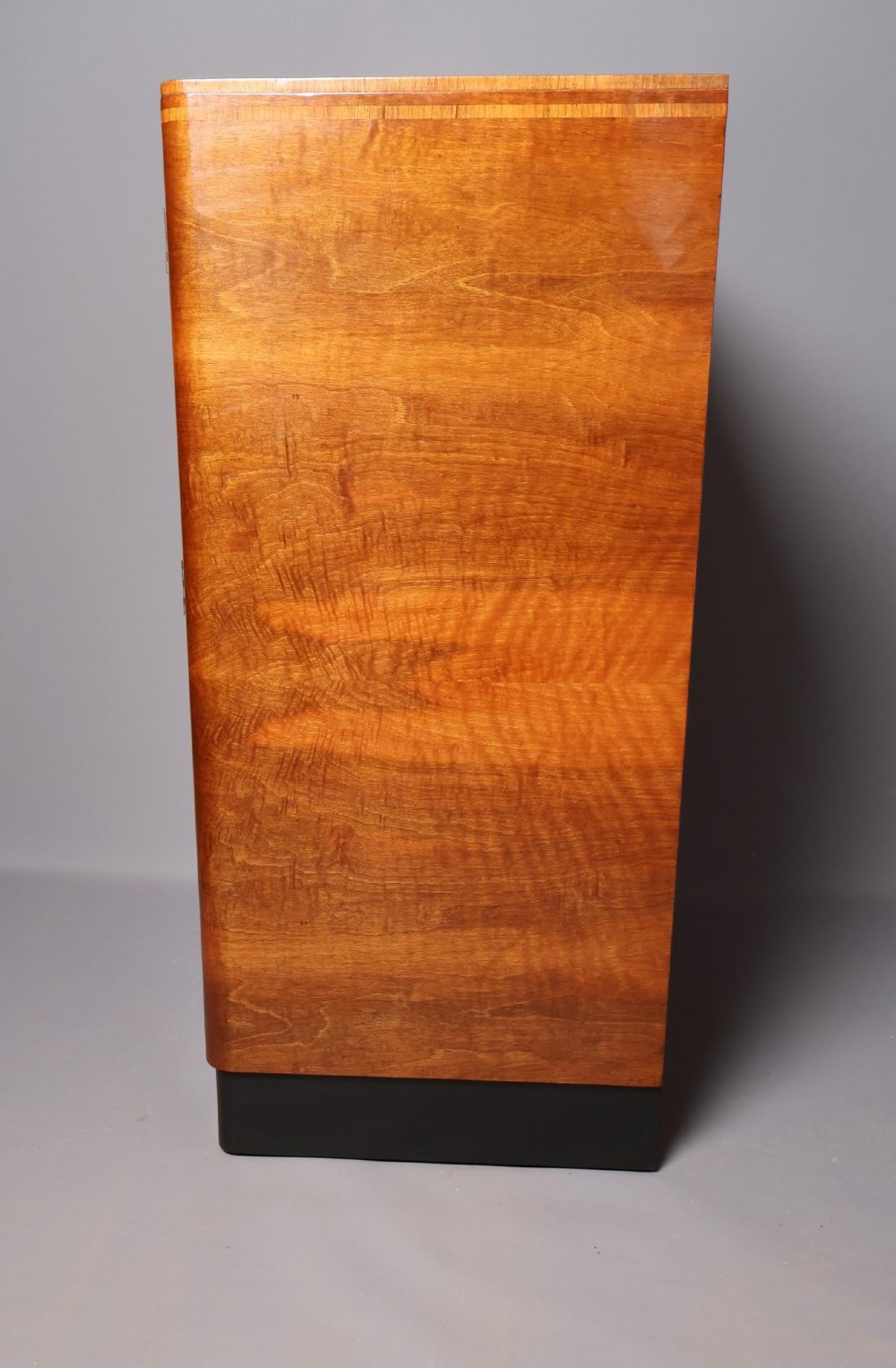 An Art Deco burr walnut compactum wardrobe featuring upper double doors, two long lower drawers, black curved handles, and an ebonised plinth. View XI