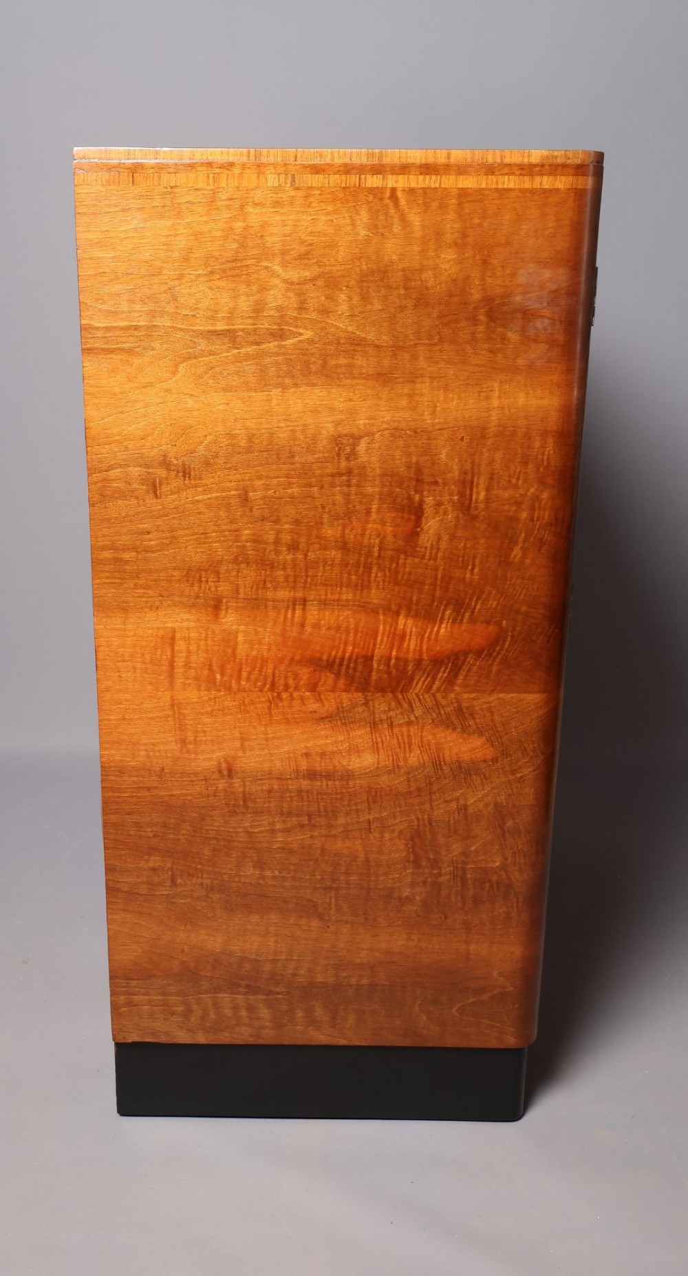 An Art Deco burr walnut compactum wardrobe featuring upper double doors, two long lower drawers, black curved handles, and an ebonised plinth. View XII