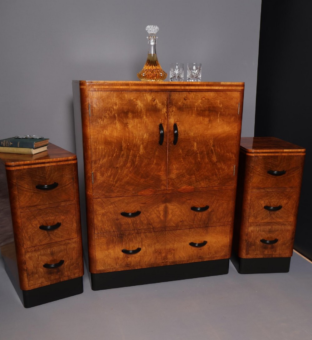 An Art Deco burr walnut compactum wardrobe featuring upper double doors, two long lower drawers, black curved handles, and an ebonised plinth. View XIV