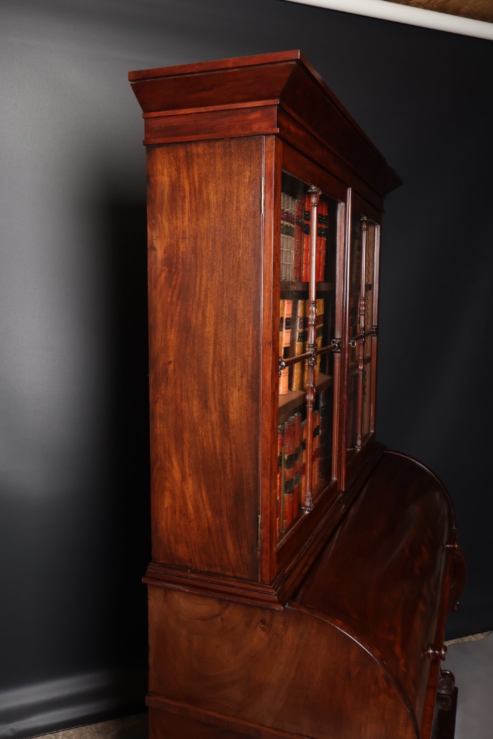 A William IV mahogany cylinder bureau bookcase featuring a two-door glazed upper cabinet, a rounded cylinder writing section, and lower cabinet doors. View VI
