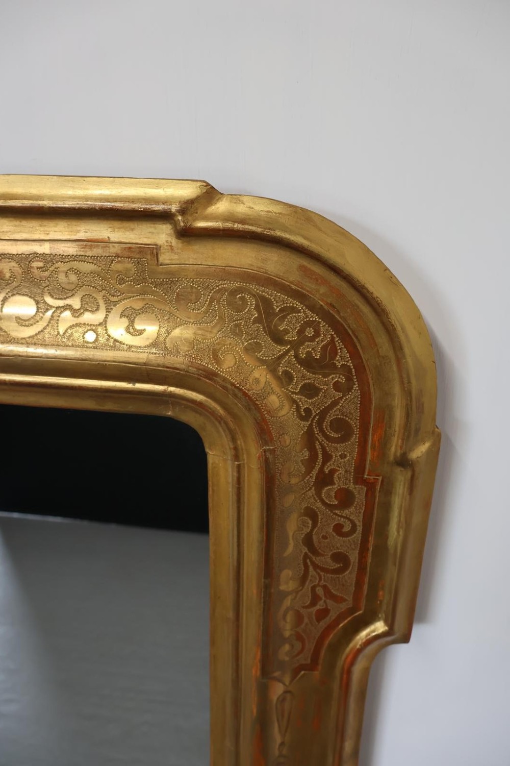 A rectangular 19th-century wall mirror featuring an ornate gold leaf giltwood frame with notched corners and incised scrollwork patterns. View III